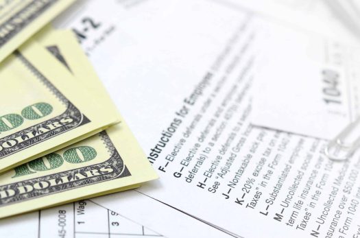 The pen, notebook and dollar bills is lies on the tax form 1040 U.S. Individual Income Tax Return. The time to pay taxes